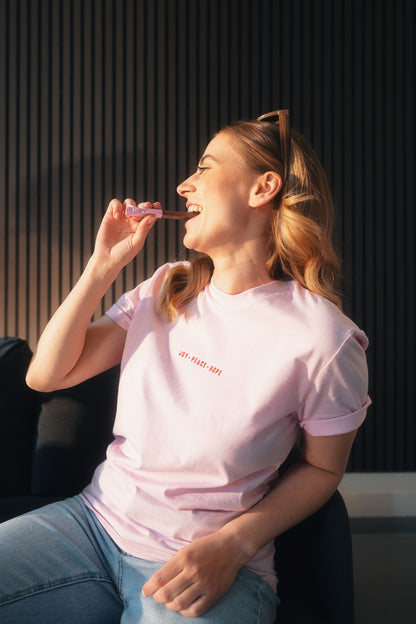 Model Oberkörperaufnahme sitzend, Produkt T-Shirt, Motiv Joy Peace Hope, Farbe Cotton Pink