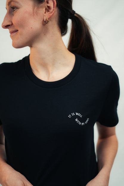 Model präsentiert Mission One More schwarzes T-Shirt "It is well" mit hochwertiger Stoffqualität Bio-Baumwolle