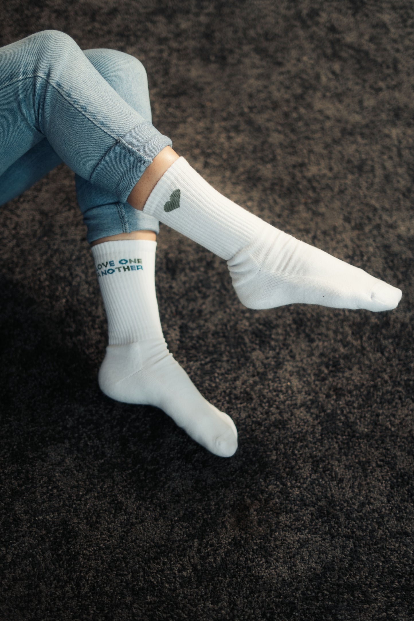 Model trägt Mission One More weiße Socken mit zeitloser christlicher Gestaltung "Love One Another"