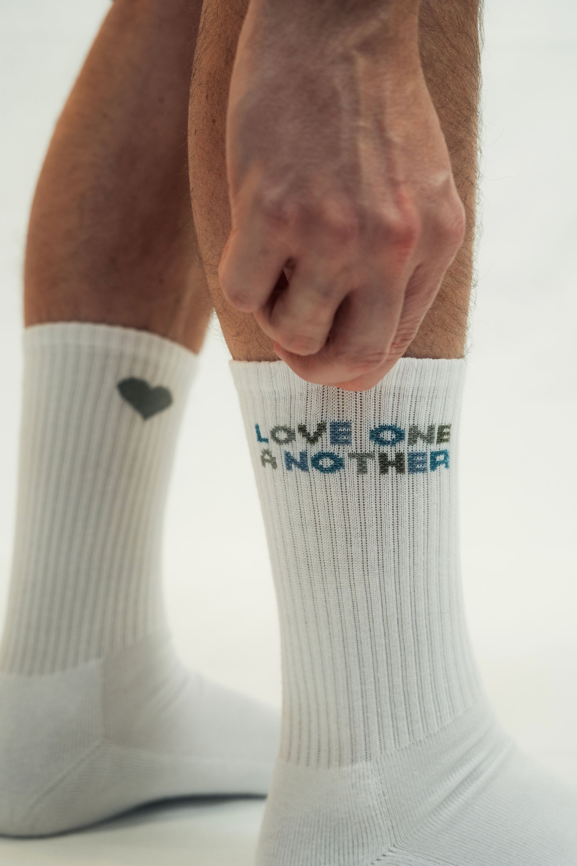 Mission One More Socken in weiß nachhaltige Herstellung schlichte christliche Botschaft "Love One Another" am Model
