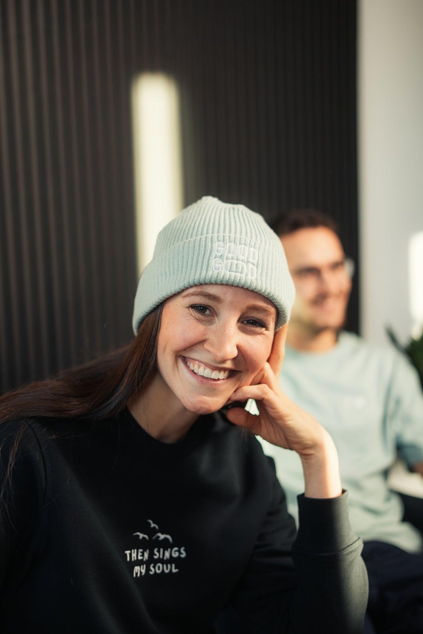 Mission One More Sweatshirt & Beanie aus Bio Baumwolle getragen im Lounge-Interior christliche Lifestyle-Mode