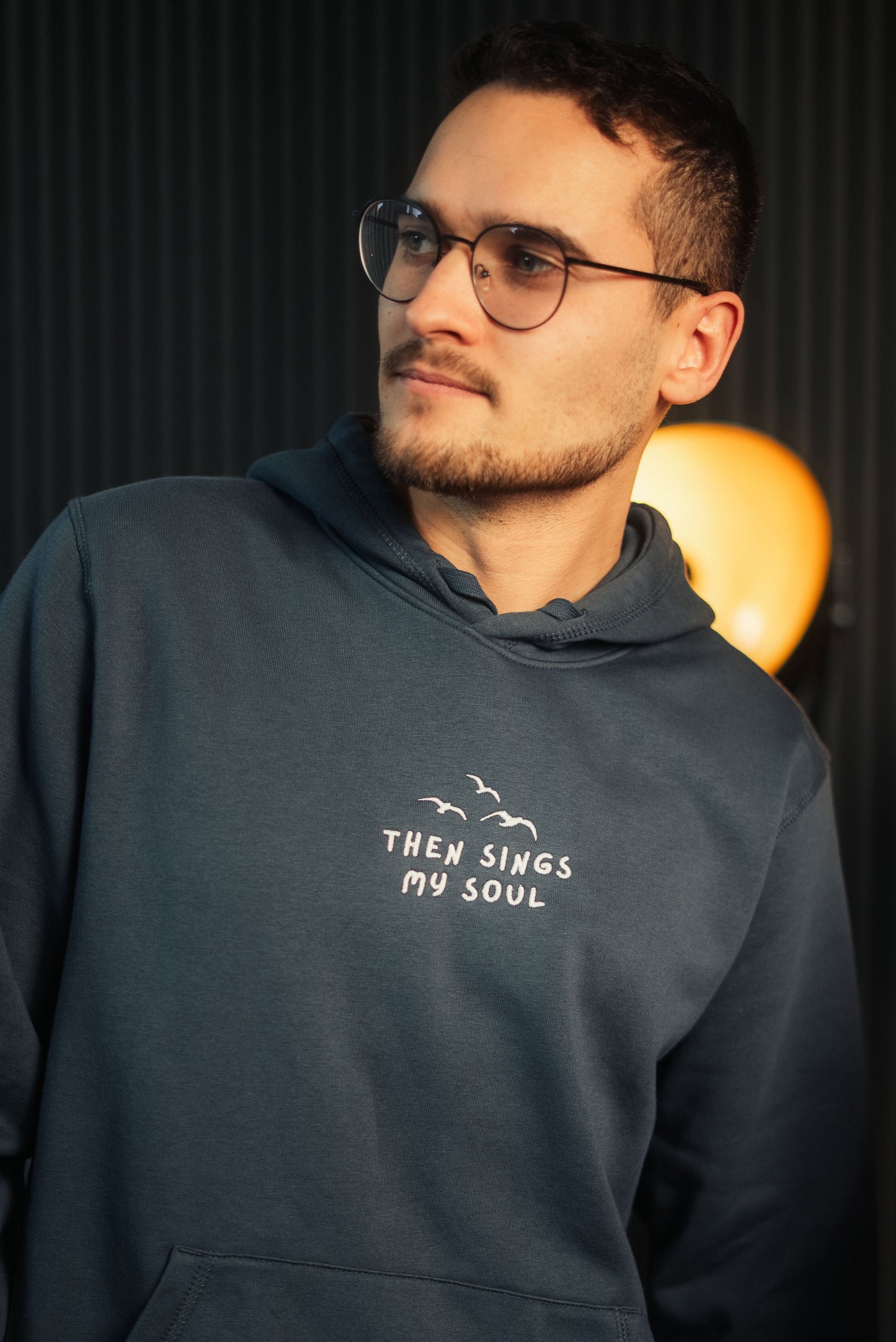 Model steht vor Lampe mit Mission One More Hoodie nachhaltiges christliches Design Then sings my Soul