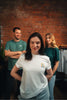 Models tragen nachhaltige Shirts mit christlichen Motiven & lächeln – Glaube, der strahlt - Gruppenaufnahme vor Backsteinwand